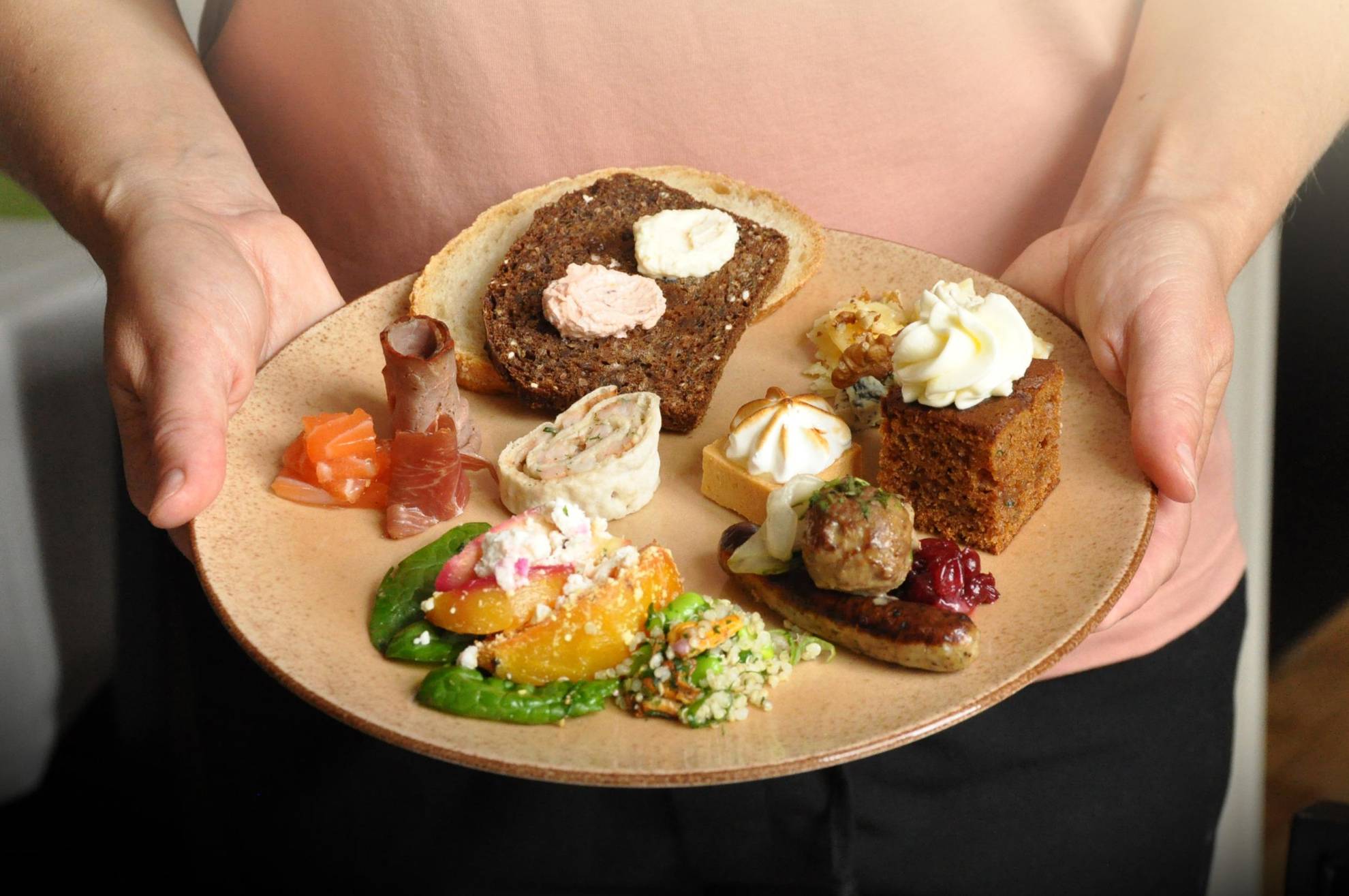Een persoon die een bord vasthoudt met verschillende soorten voedsel.