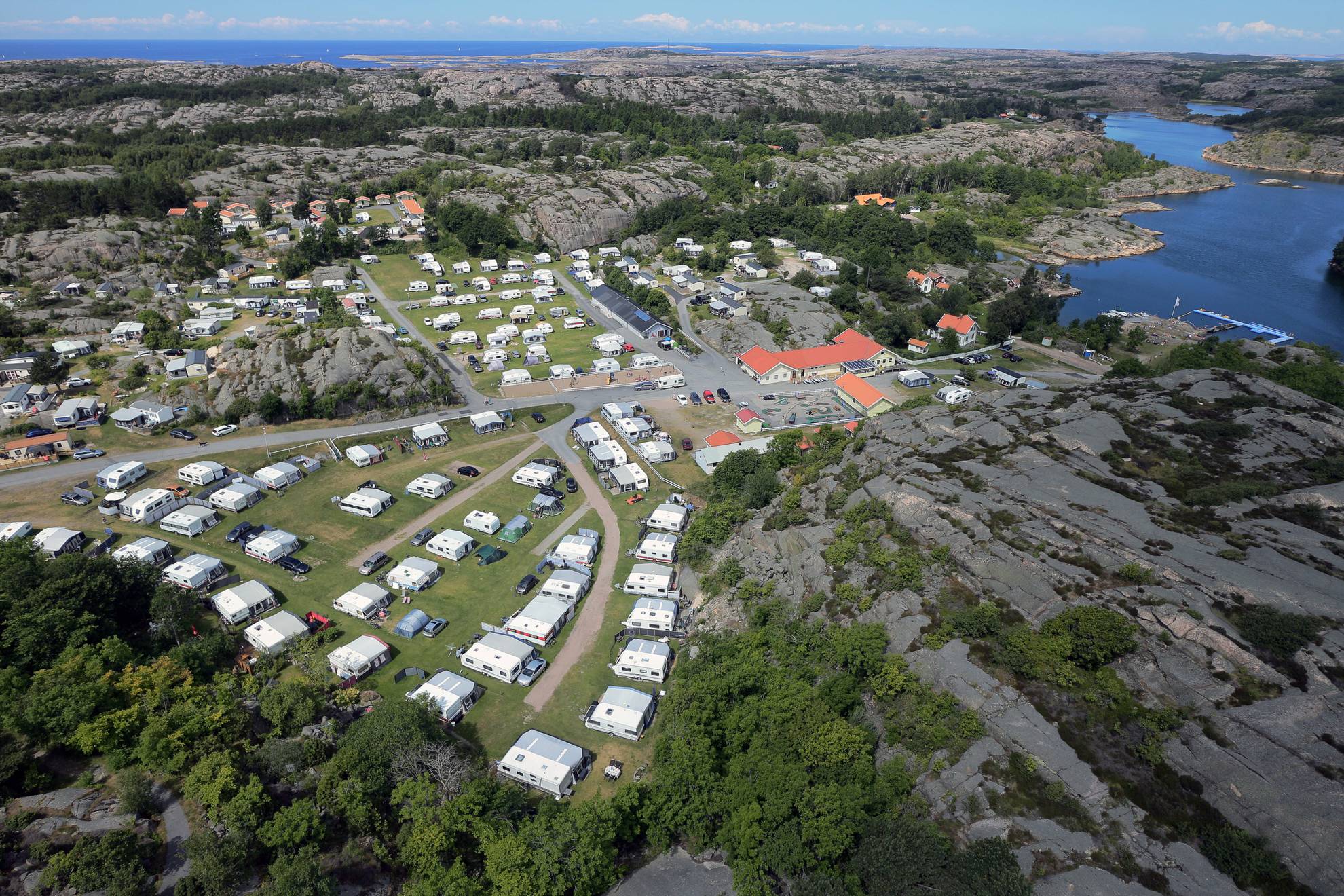 Luchtfoto van een camping aan zee. Caravans staan netjes in rijen geparkeerd.