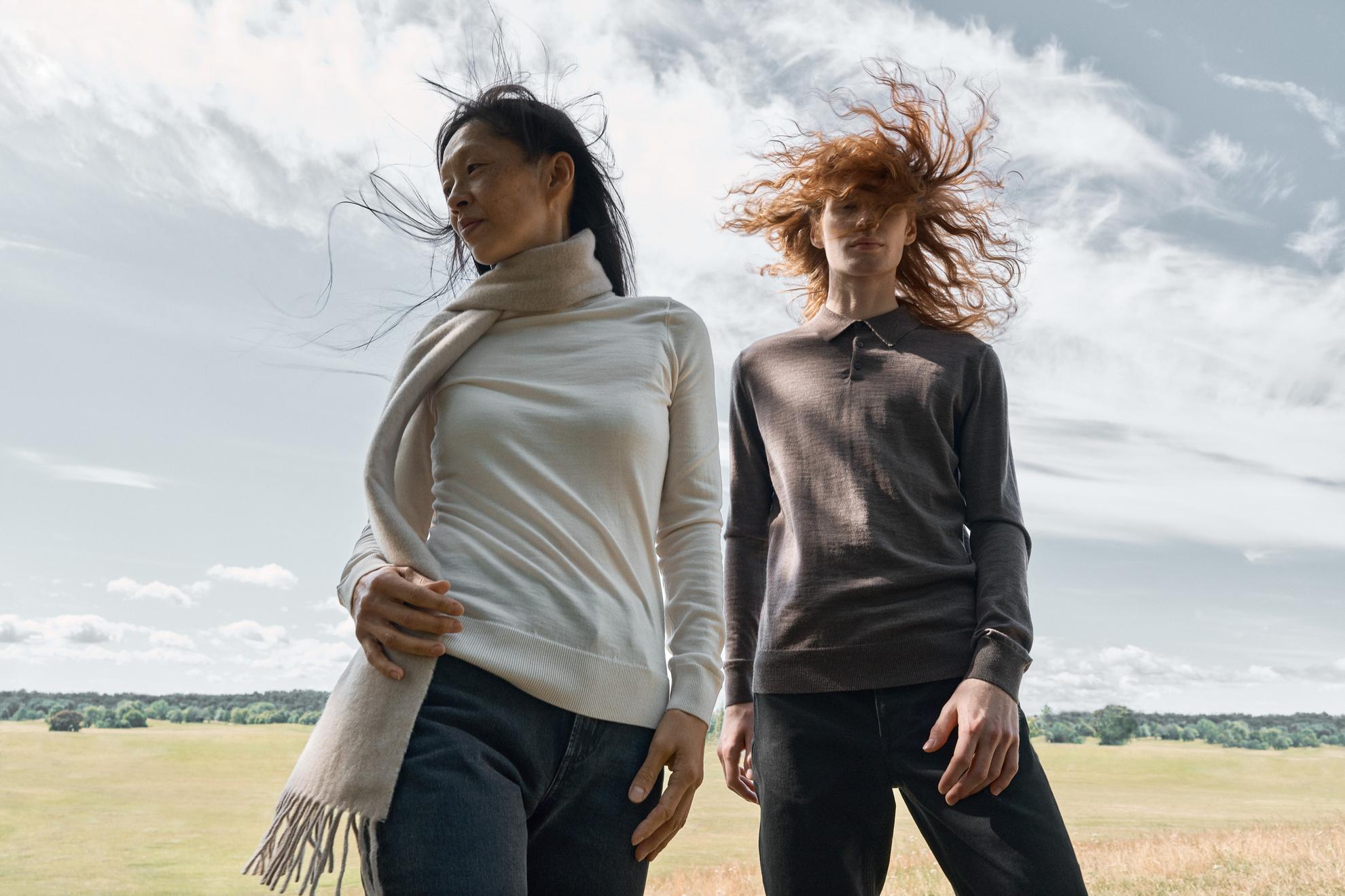 Een modeshoot van twee vrouwen die in een veld staan met de wind in hun haar.