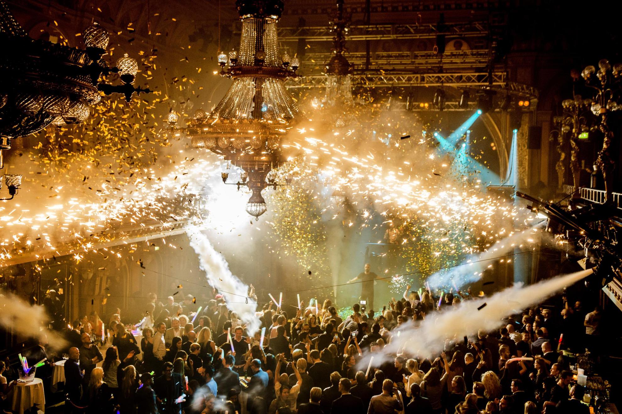 Berns nachtclub gevuld met dansende mensen. Rook van rookkanonnen en confetti in de lucht.