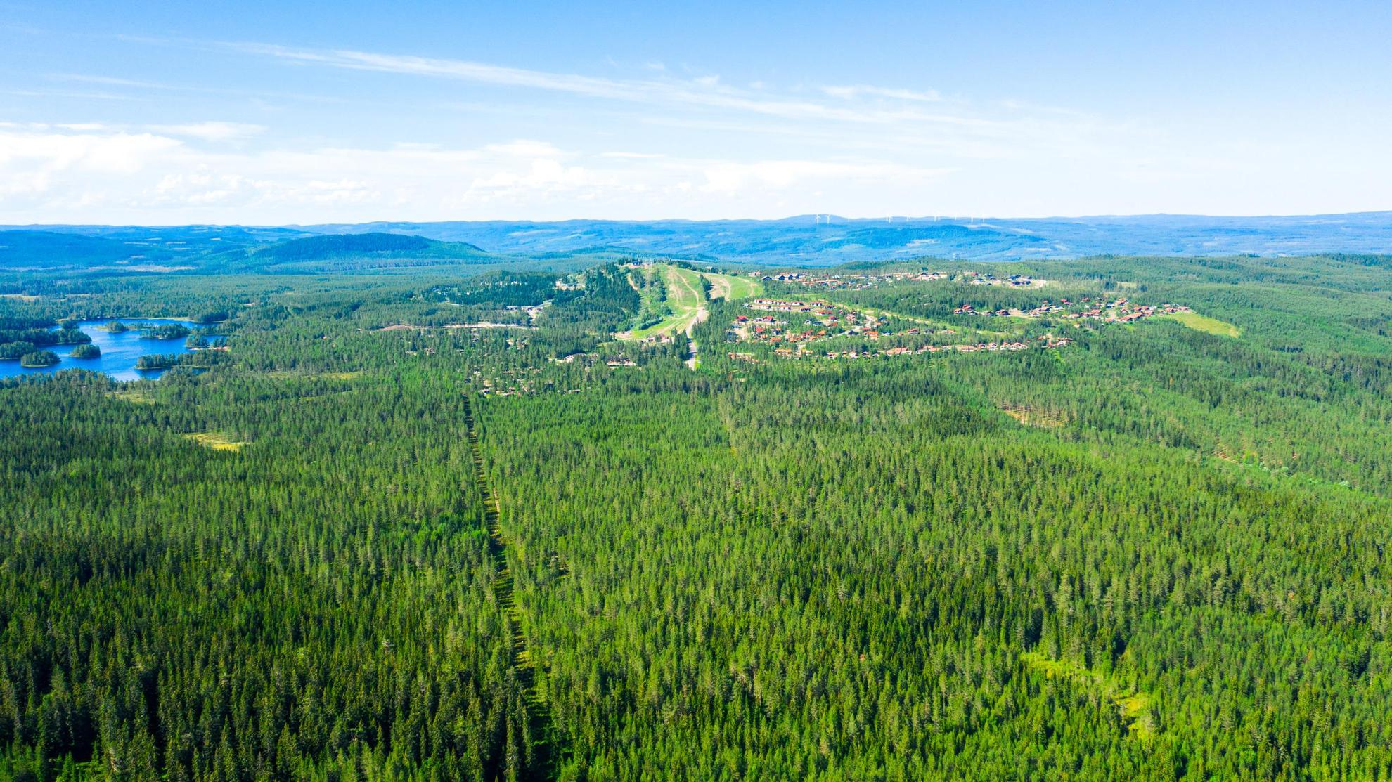 Een luchtfoto van Orsa Grönklitt met zijn huizen en omliggende bossen en meren.