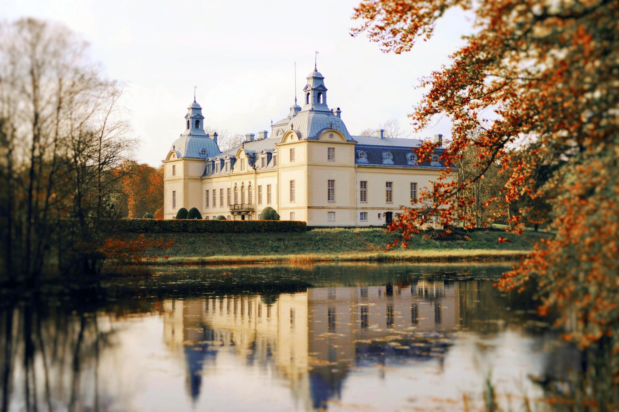 Kasteel Kronovall naast een meer in de herfst. Het kasteel wordt weerspiegeld in het water.