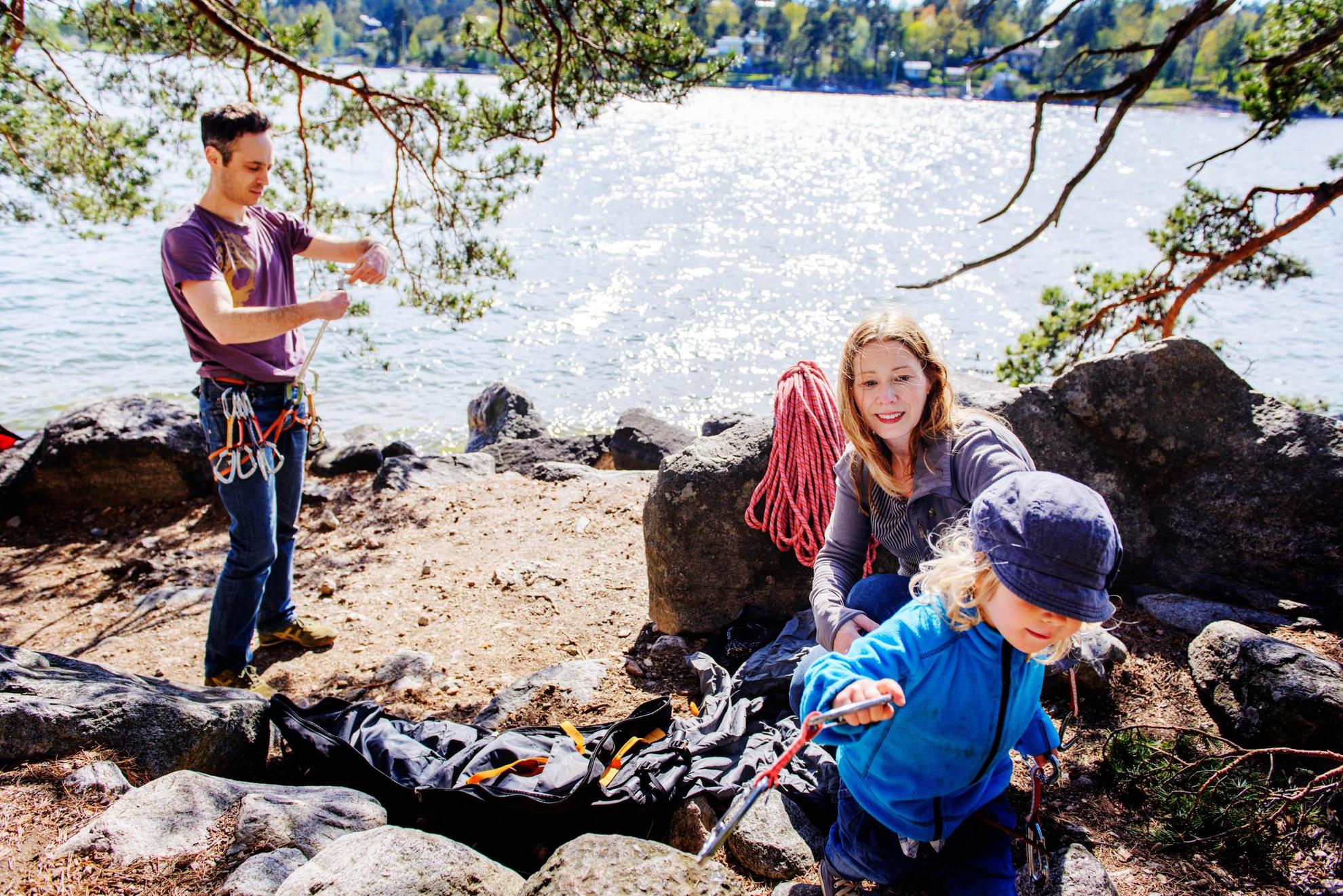Een gezin aan een meer in Bohuslän. De man bereidt zijn uitrusting voor. Een vrouw kijkt toe hoe een kind wegrent met karabijnhaken in zijn of haar hand.