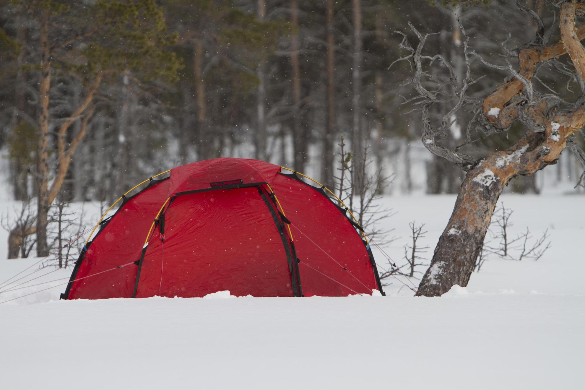 Een rode tent opgezet in de sneeuw.