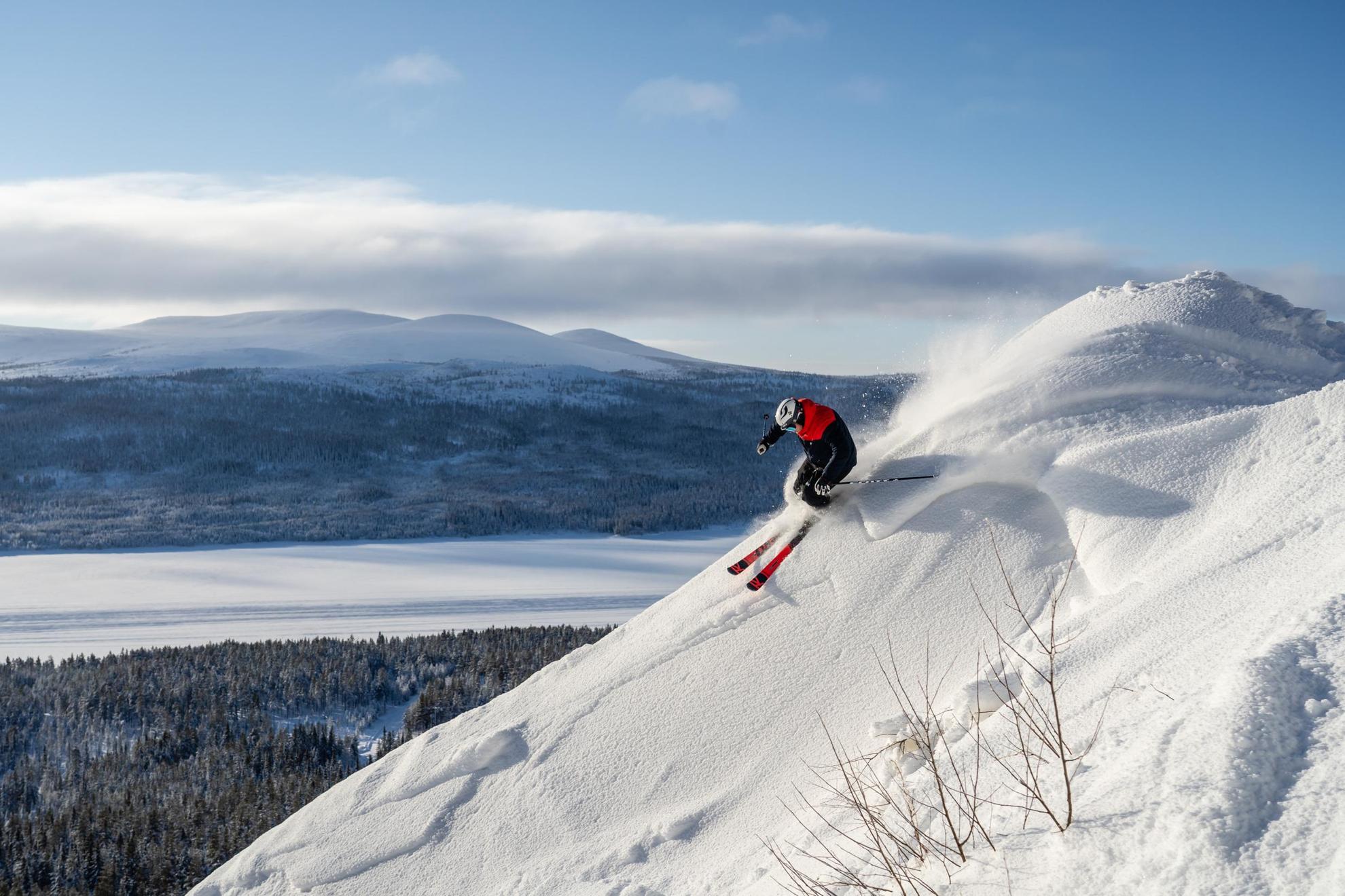 Een persoon is aan het skiën op een berg met uitzicht op een besneeuwd landschap op de achtergrond.