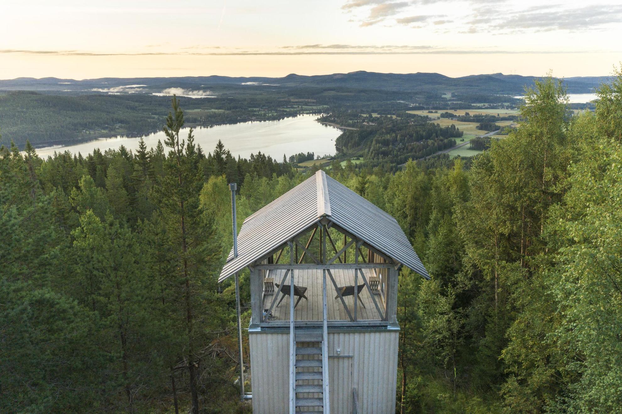 Buitenkant van een minimalistisch huisje midden in de natuur, met een houten structuur en een open loft met uitzicht op de bergen en het bos in Hälsingland.