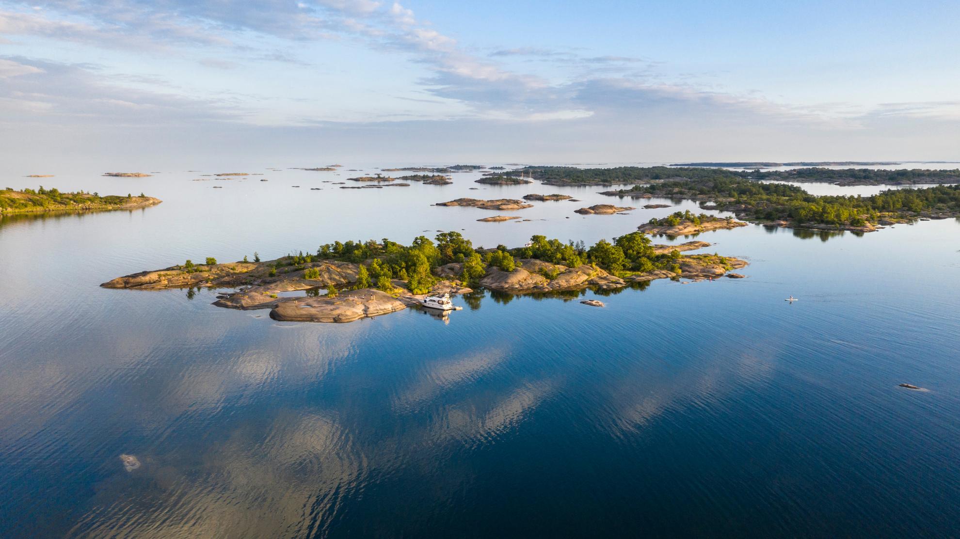 Luchtfoto van een boot naast een eiland in de archipel van Stockholm tijdens een zomerdag.