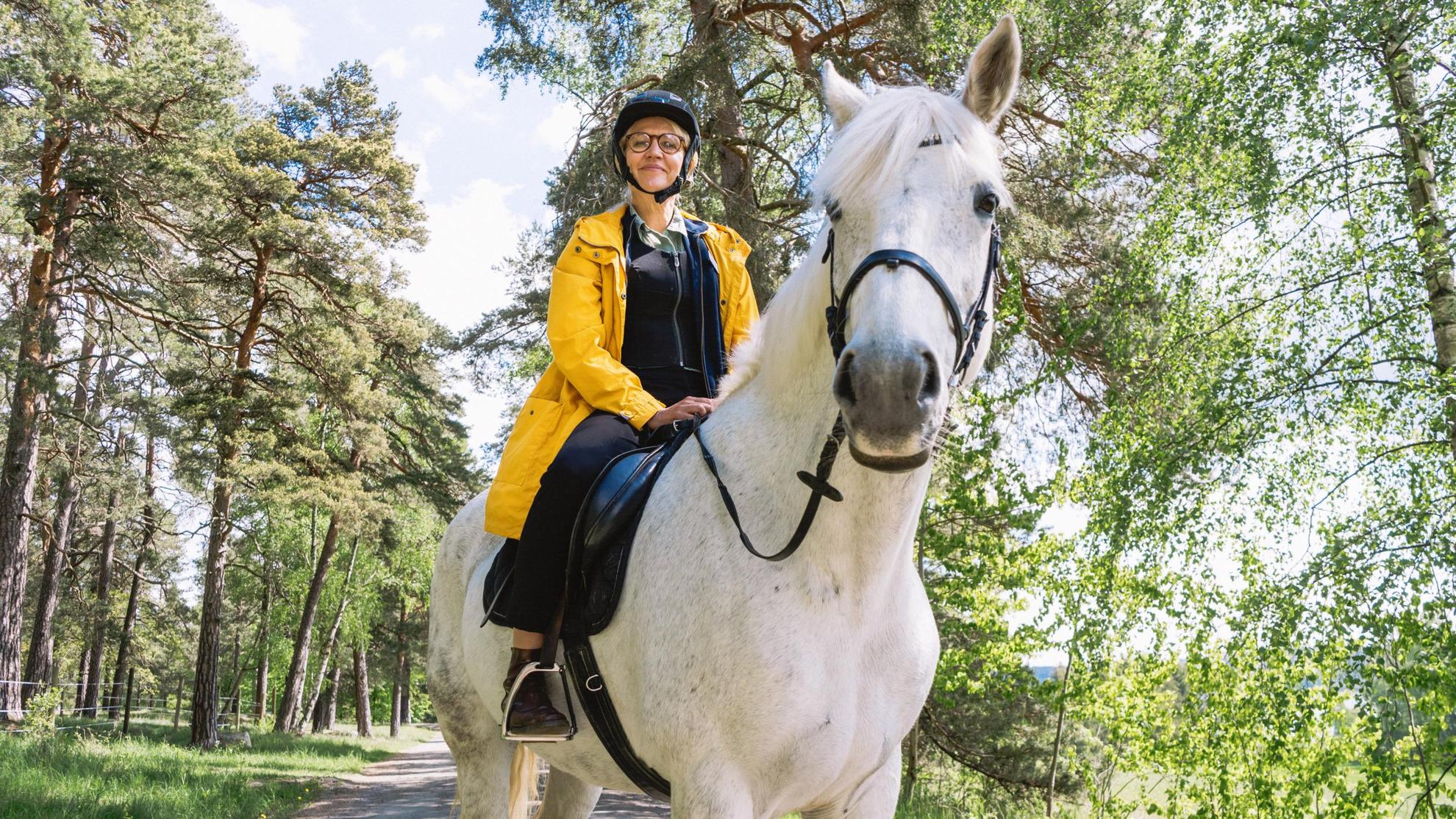 Een vrouw zit op een wit paard.