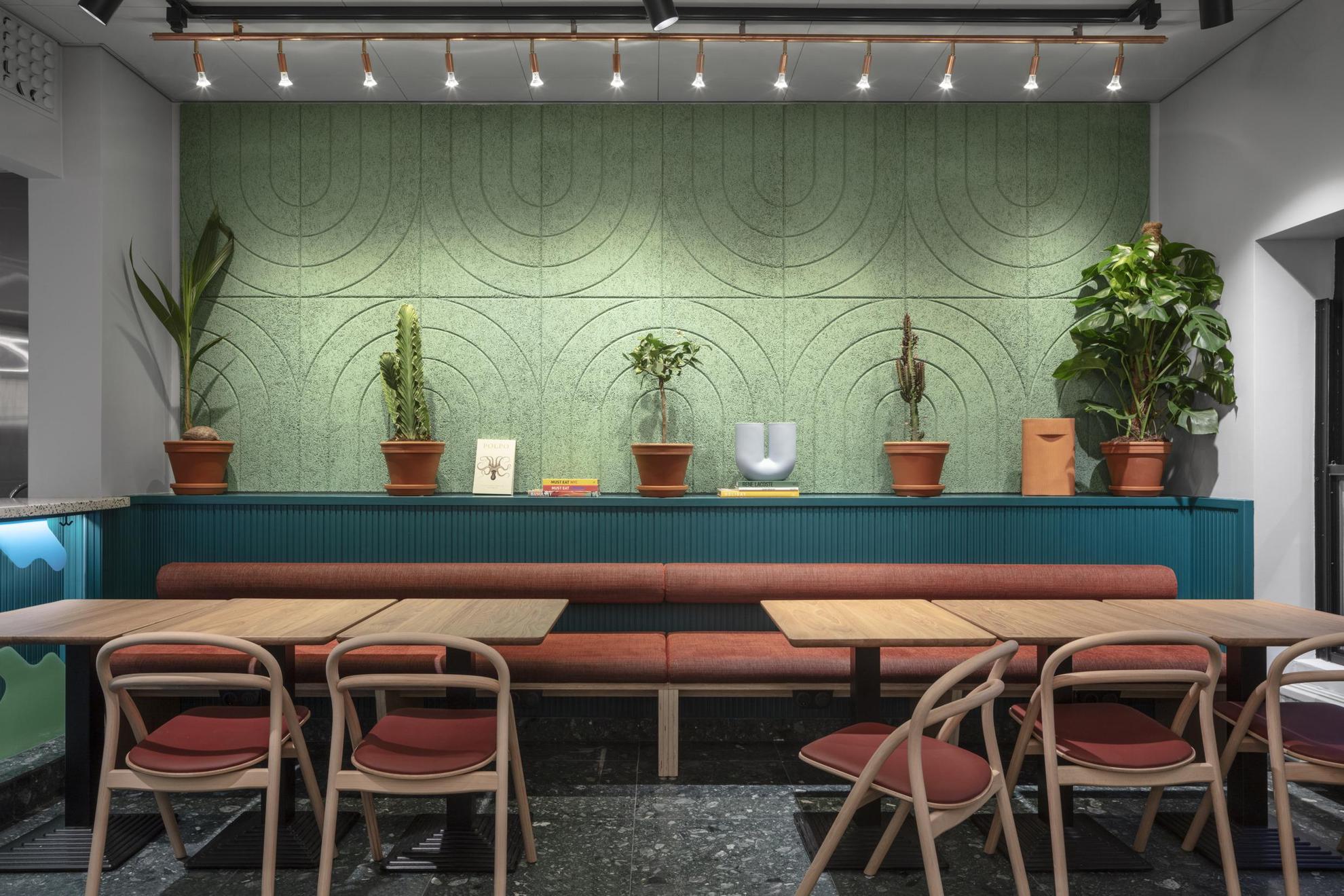 Een zithoek. Een paar planten sieren de groen met blauwe muur achter de tafel.