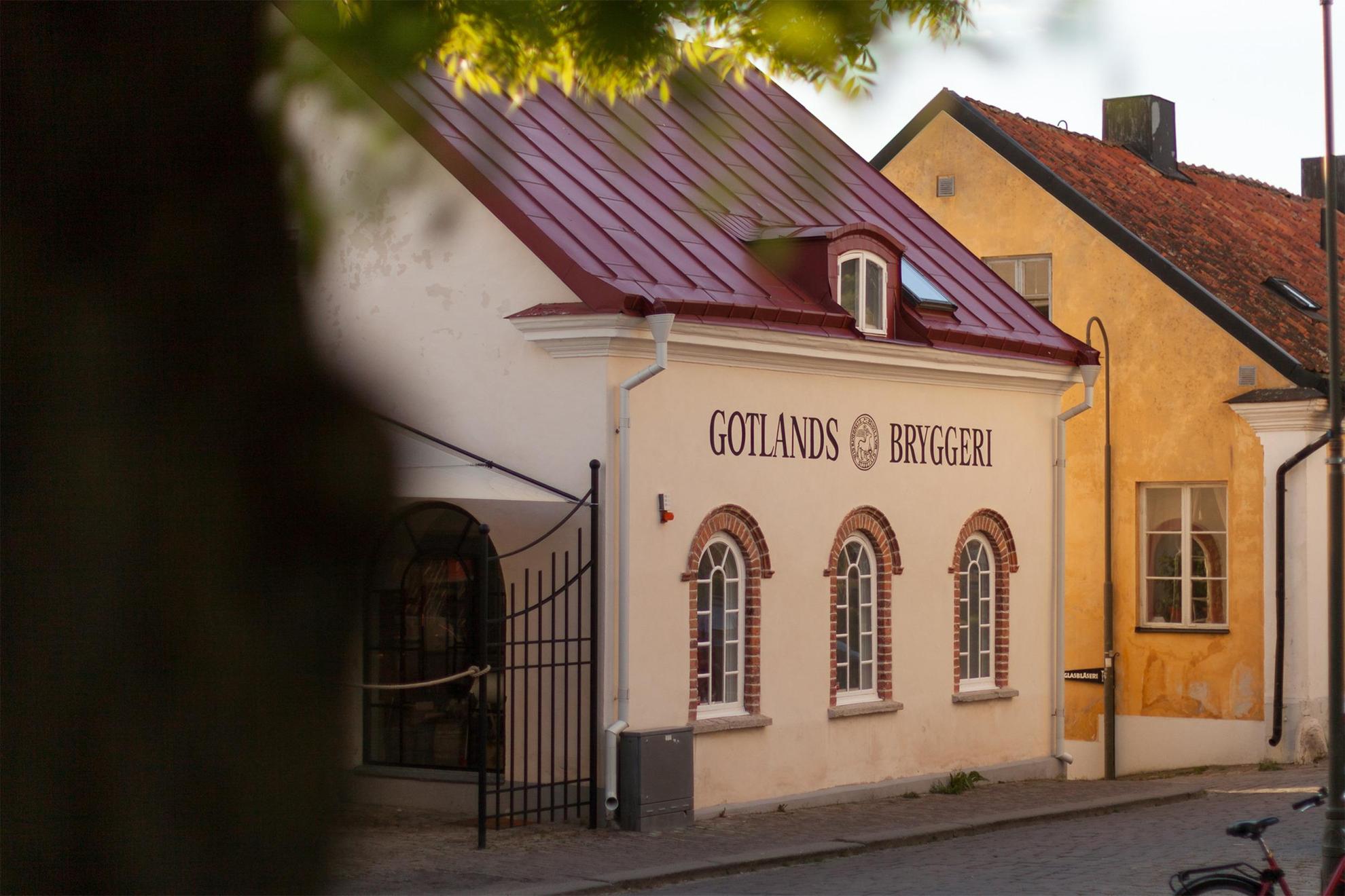 Een straat met een wit huis. Op het huis staat "Gotlands Bryggeri".
