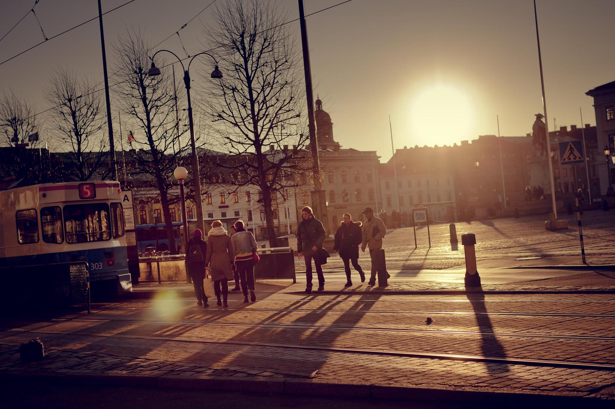 Göteborg met de ondergaande zon. Een blauwe tram op de voorgrond en gebouwen erachter.