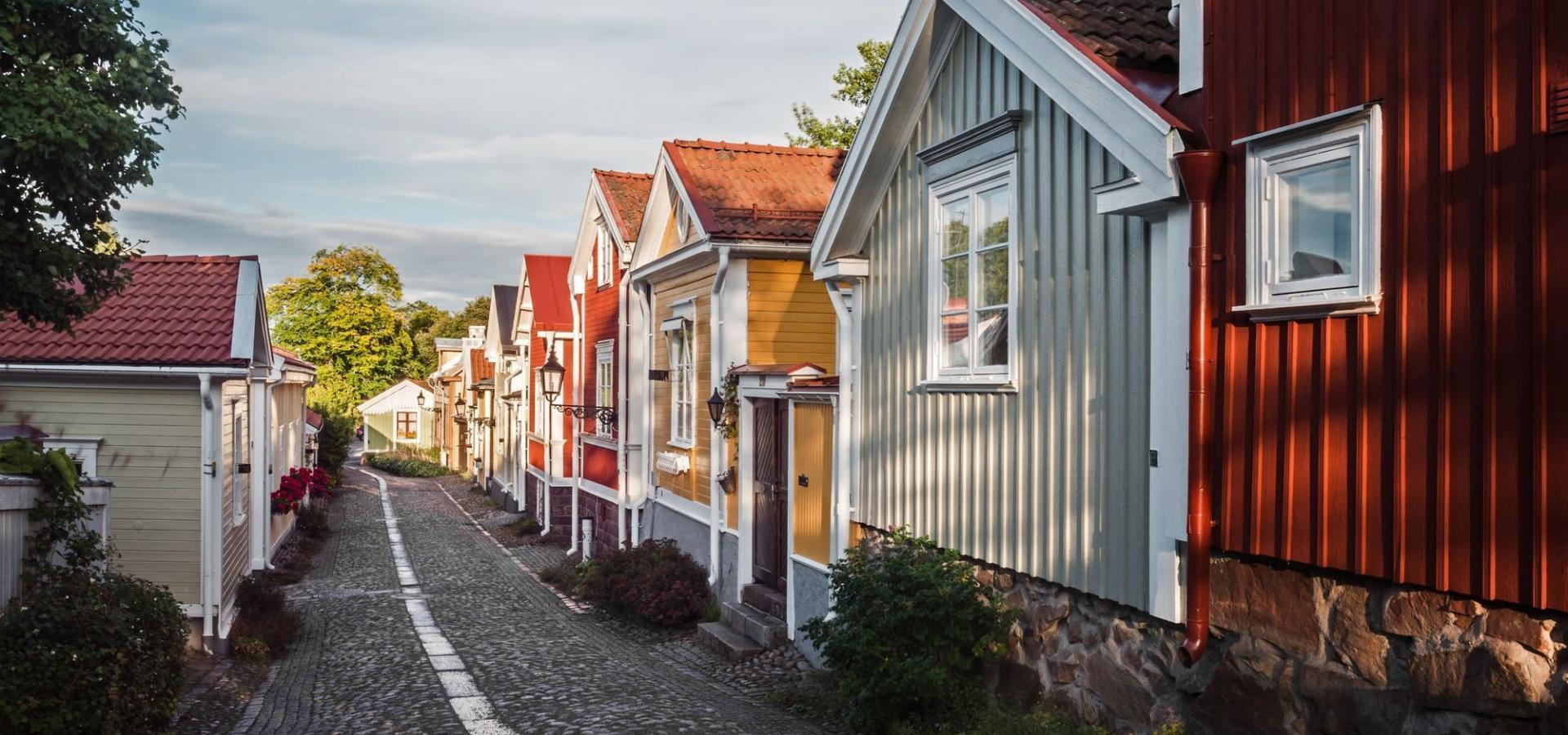 Een geplaveide straat strekt zich uit tussen pastelkleurige houten huizen.