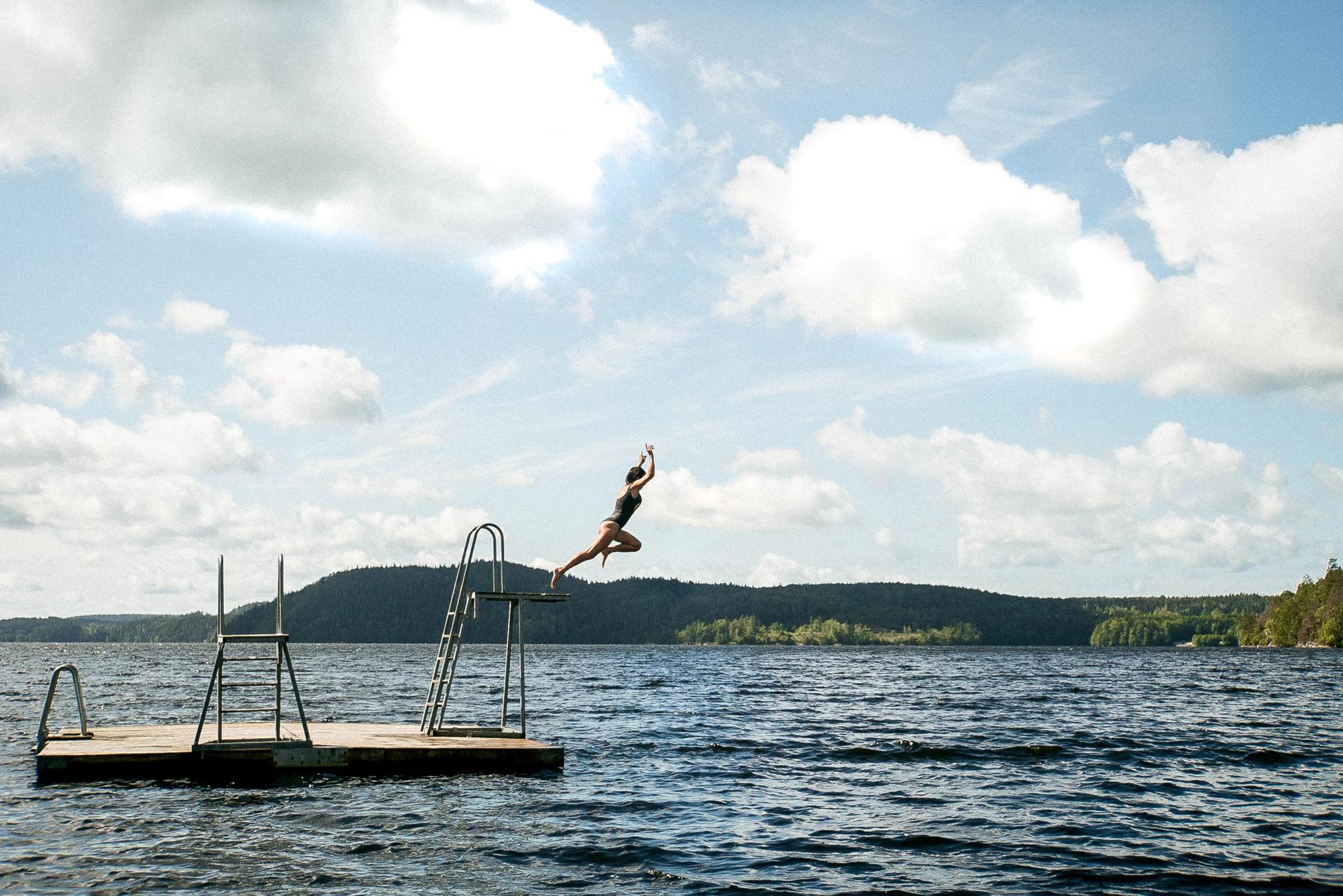 Een vrouw die vanaf een duiktoren in zee springt.
