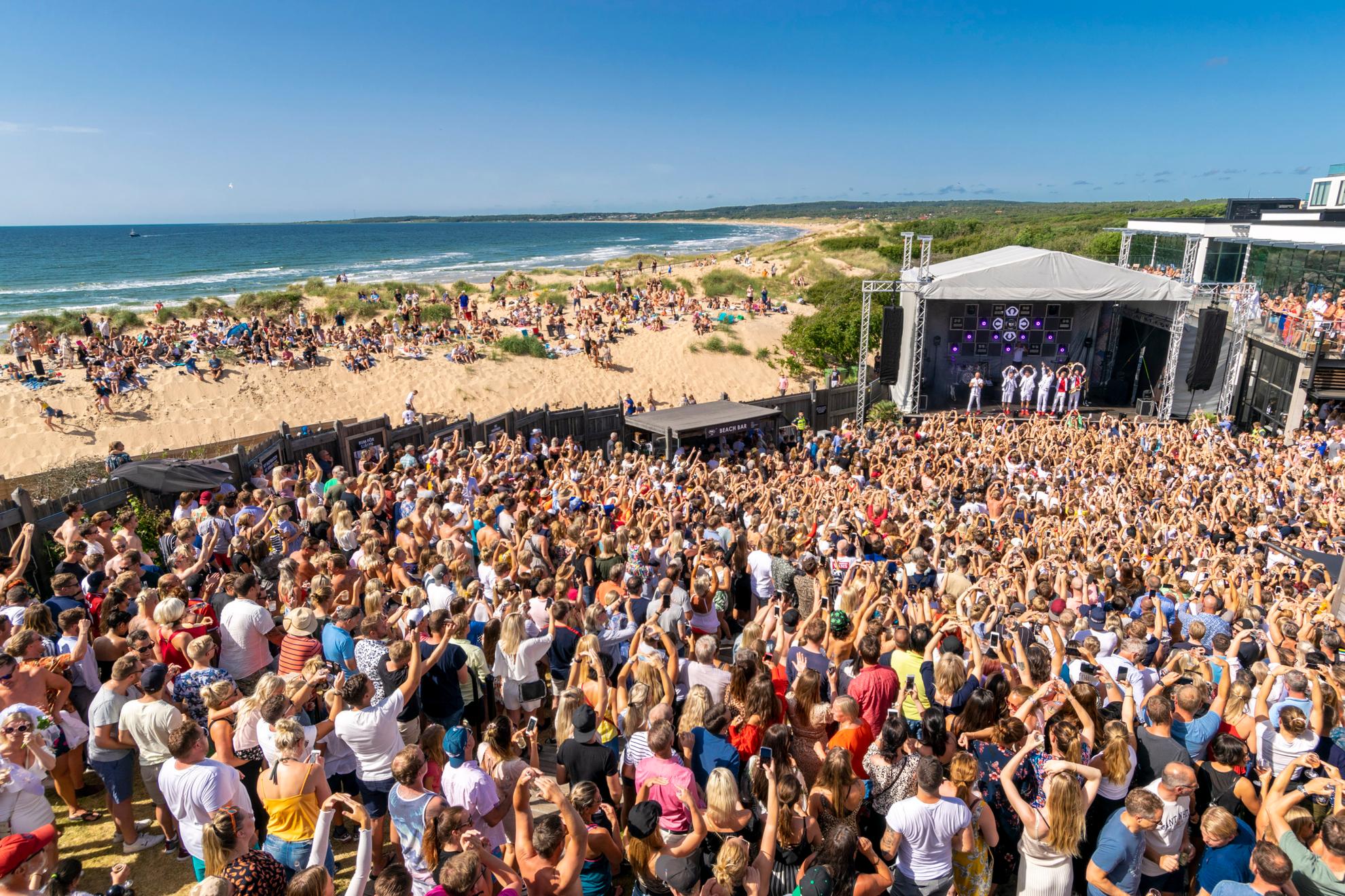 Een grote menigte op een podium op een strand aan zee.
